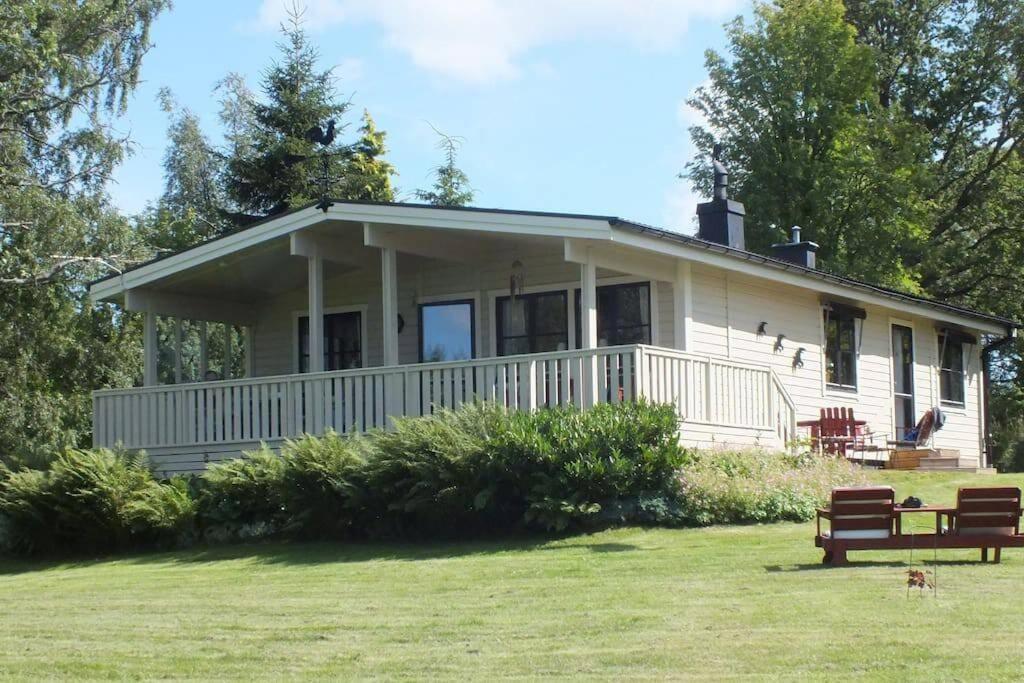 una casa blanca con un banco delante en Ferienhaus Smultronsställe Hjo, Vättern en Hjo