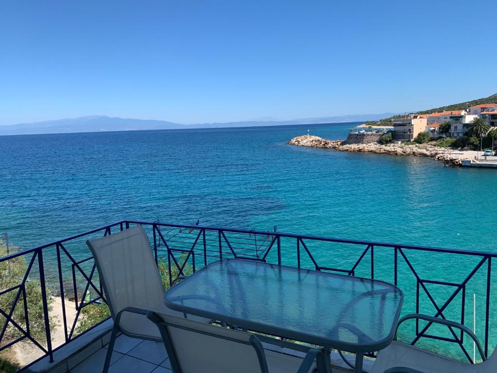 a balcony with a glass table and chairs overlooking the water at Studios Apollonia in Skala Marion