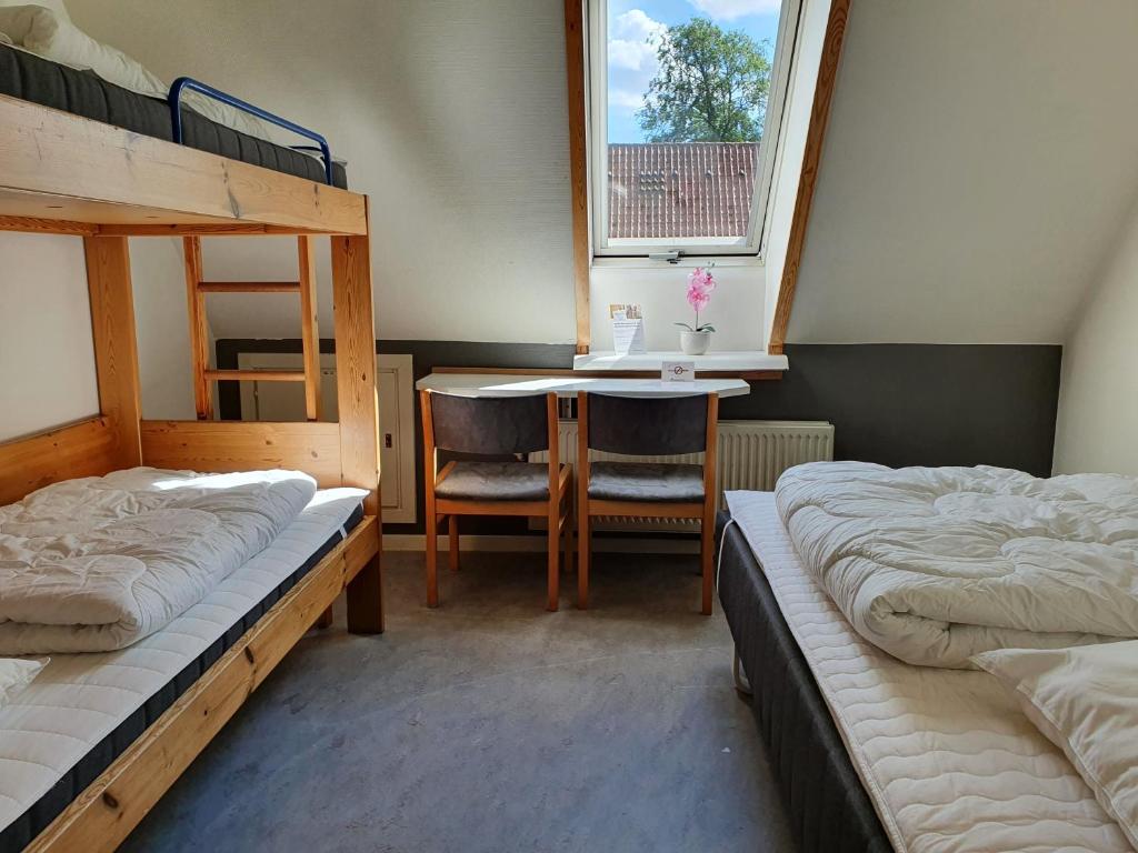 a room with two bunk beds and a table and a desk at Danhostel Ringsted in Ringsted