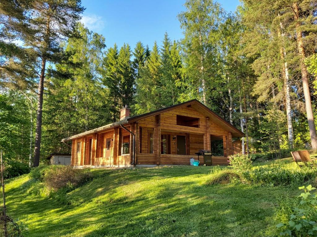 uma cabana de madeira na floresta com um quintal em Kuhajärven Suviranta cottage em Vihtavuori