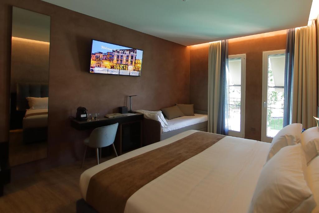a hotel room with a bed and a tv on the wall at Hotel Bell'arrivo by Dori in Peschiera del Garda