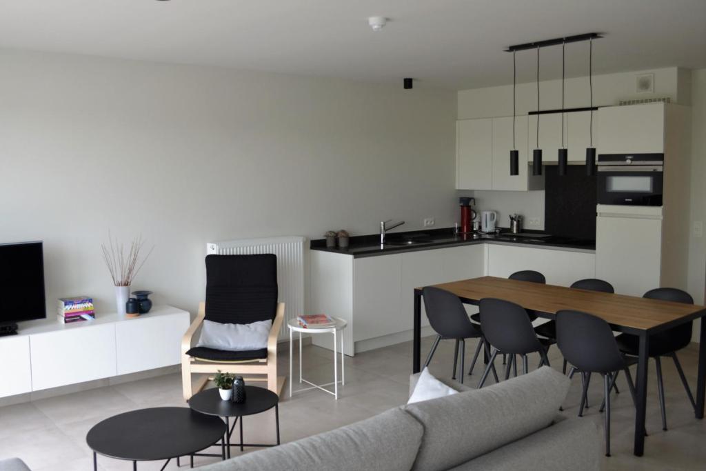 ein Wohnzimmer mit einem Tisch und Stühlen sowie eine Küche in der Unterkunft Karthuizer Duinpoort in Nieuwpoort