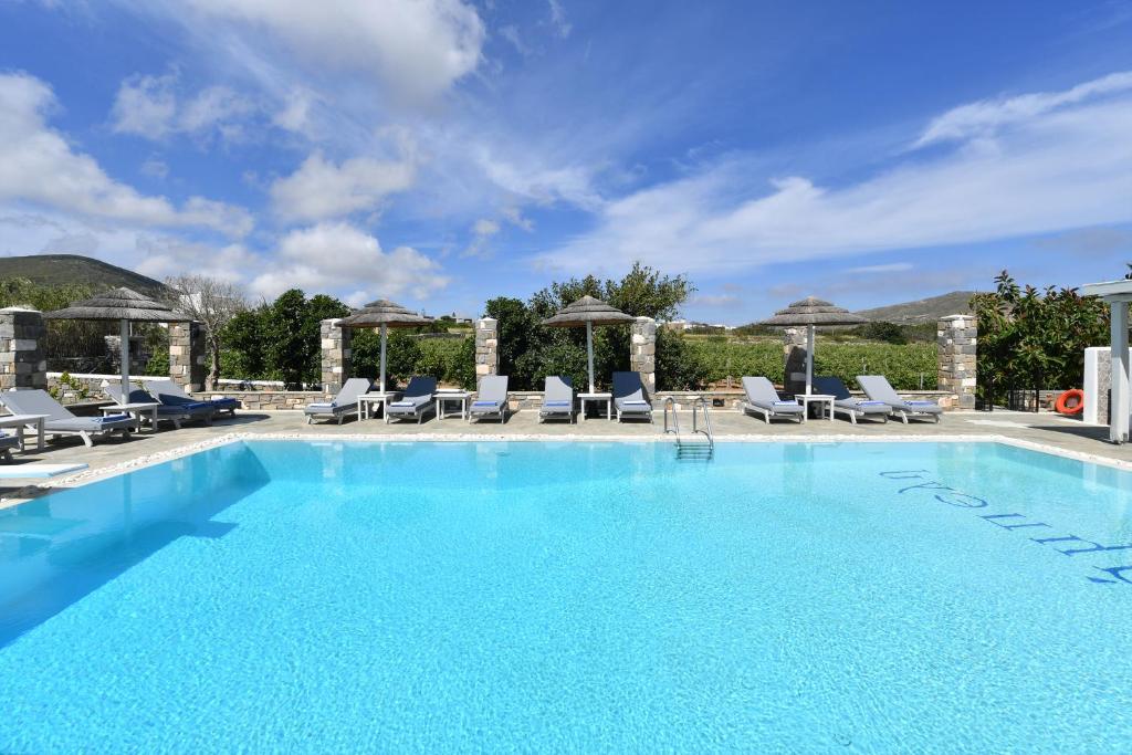 einen großen Pool mit Liegestühlen und Sonnenschirmen in der Unterkunft Agrabeli Paros in Naoussa