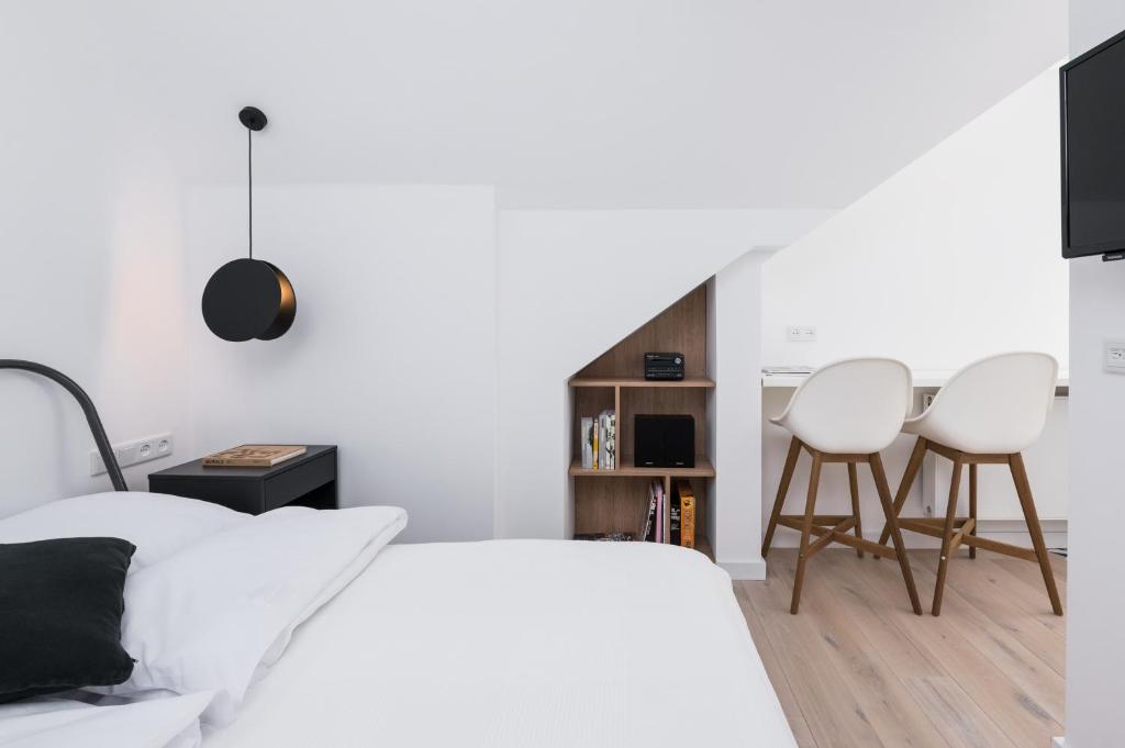 a bedroom with a bed and two white chairs at Chillax Apartments in Zator