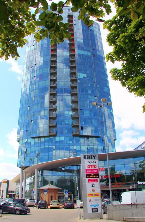 a large glass building with a sign in front of it at Helios Luxury apartment in Vilnius skyscraper in Vilnius