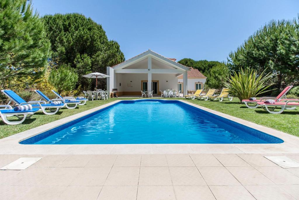 een zwembad in de tuin van een huis met stoelen bij Quinta do Peru I in Quinta do Conde