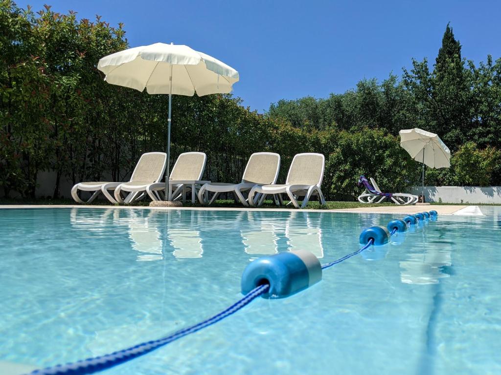 una piscina con sillas y sombrilla en Residence Corte del Bosco, en Garda