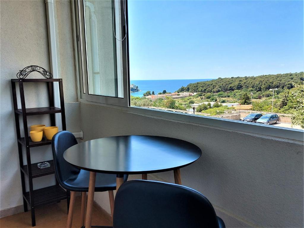 einen Tisch und zwei Stühle in einem Zimmer mit Fenster in der Unterkunft Sunset Apartment in Pula