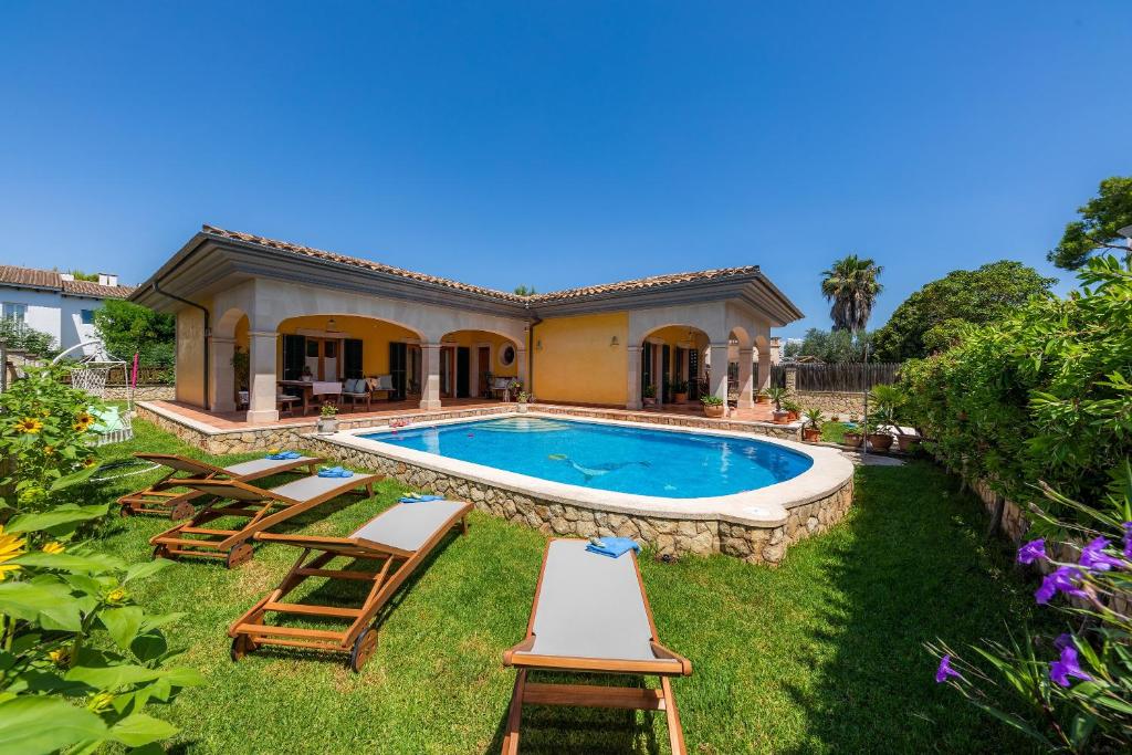 einen Hinterhof mit Pool und Stühlen und ein Haus in der Unterkunft Ca Na Rosa in Alcúdia