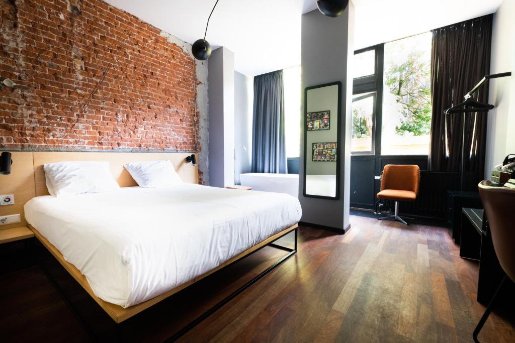 una camera da letto con un muro di mattoni e un letto di The Arcade Hotel Amsterdam ad Amsterdam