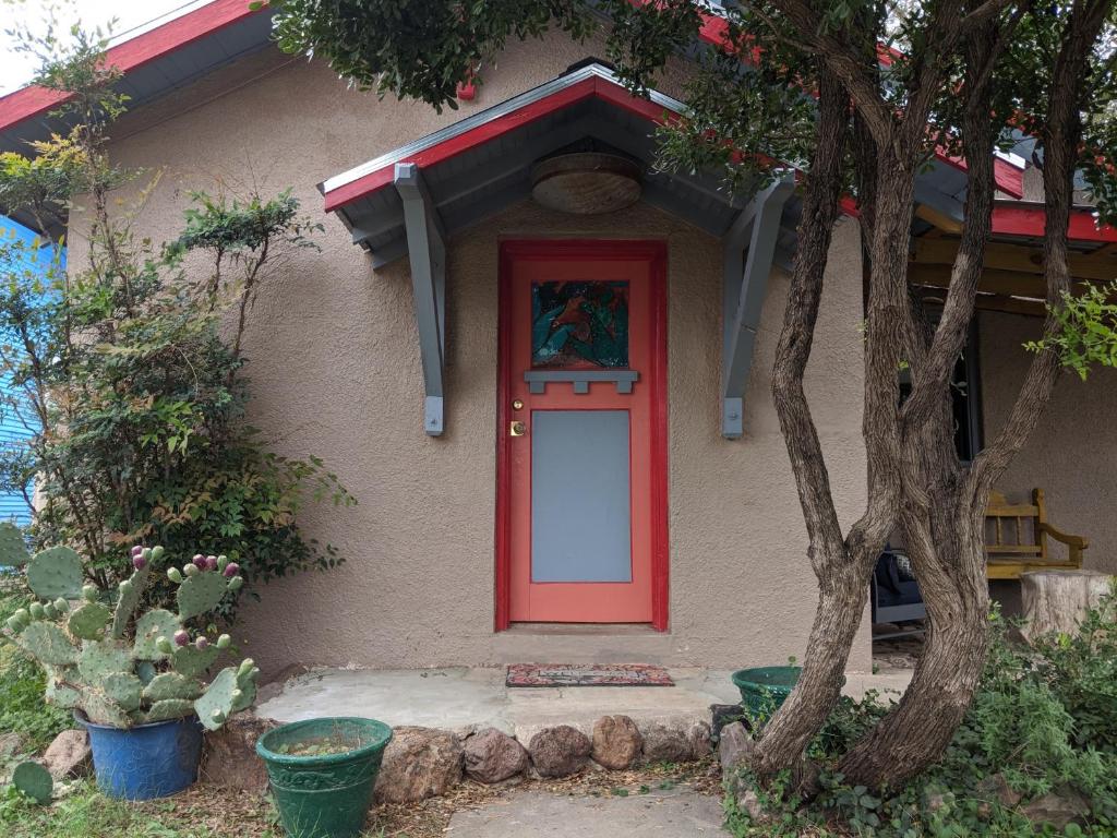 eine rote Tür an einem Haus mit einem Baum in der Unterkunft El Nopal Casita-Close to Sul Ross State University in Alpine