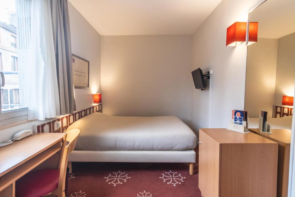 a hotel room with a bed and a desk at Hotel Ours Blanc - Place Victor Hugo in Toulouse