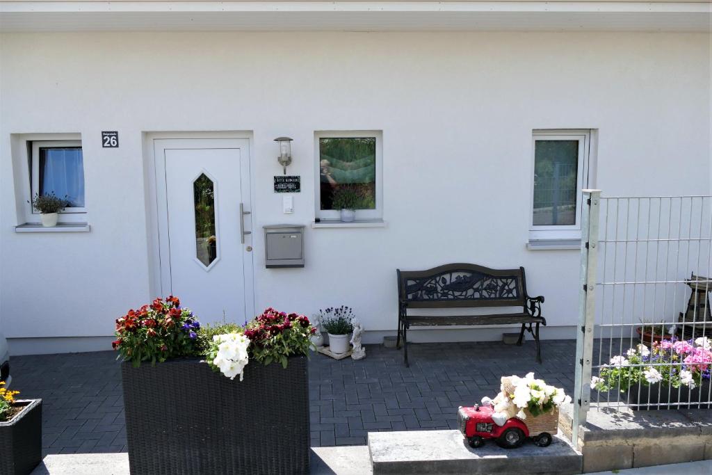 une maison blanche avec des fleurs et un banc dans l'établissement Ferienwohnung Mechernich-Eifel, à Mechernich