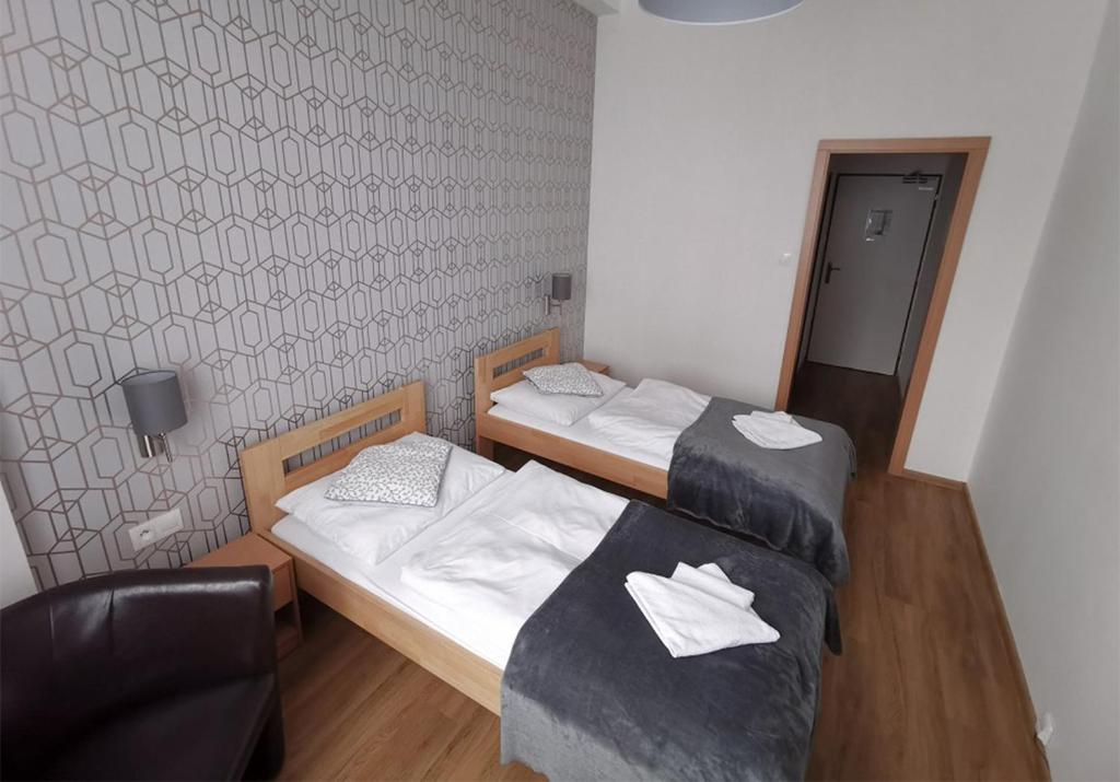 Habitación con 2 camas y una silla. en Hotel Preveza, en Spišská Nová Ves