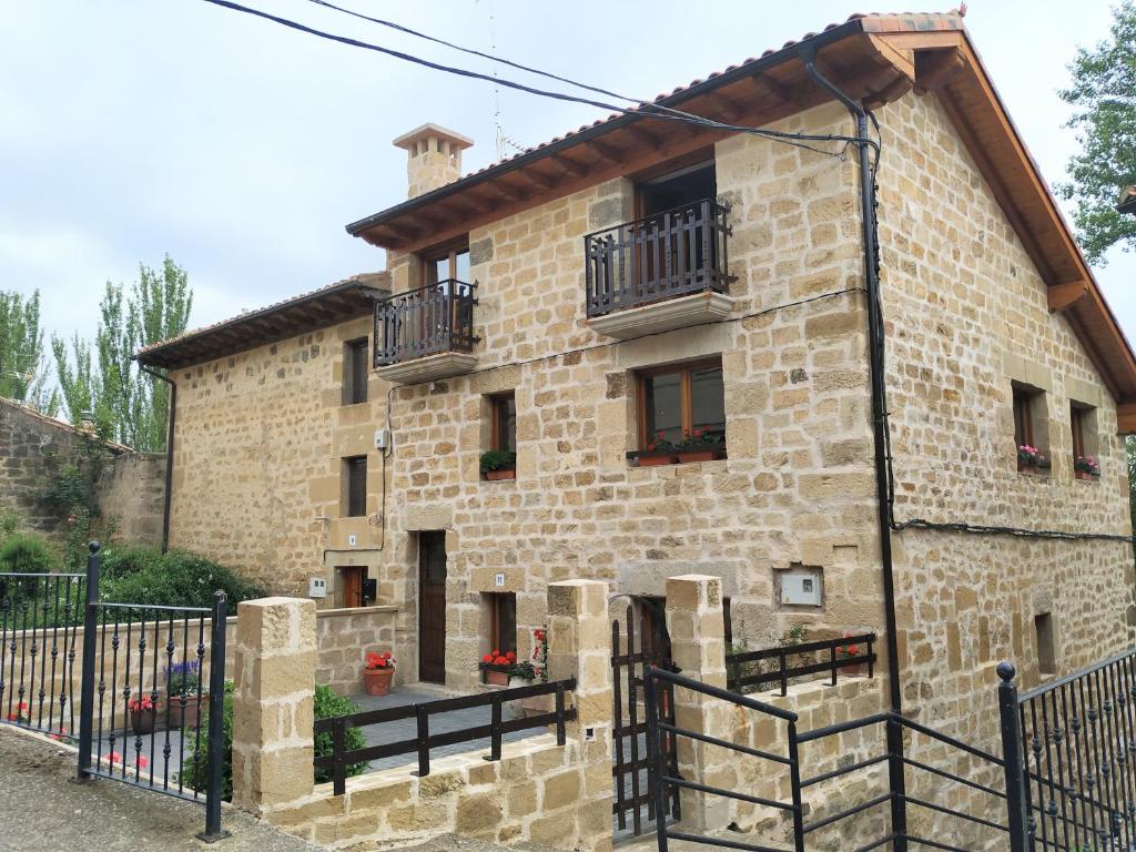 una casa de piedra con una valla negra delante de ella en La Casa de las Tinas, en Sajazarra