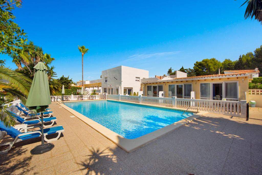 una piscina con sillas y una sombrilla junto a una casa en Aparthotel Carrio Sol - Monty´s, en Calpe