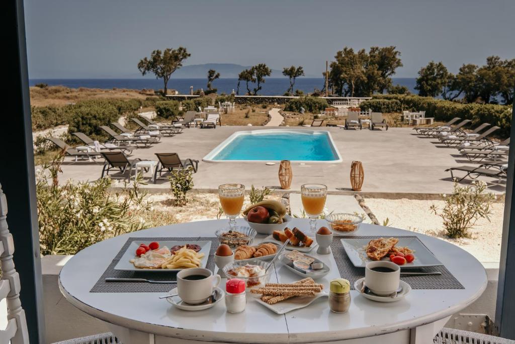 a table with food and drinks next to a pool at Mare Nostrum Santo in Oia