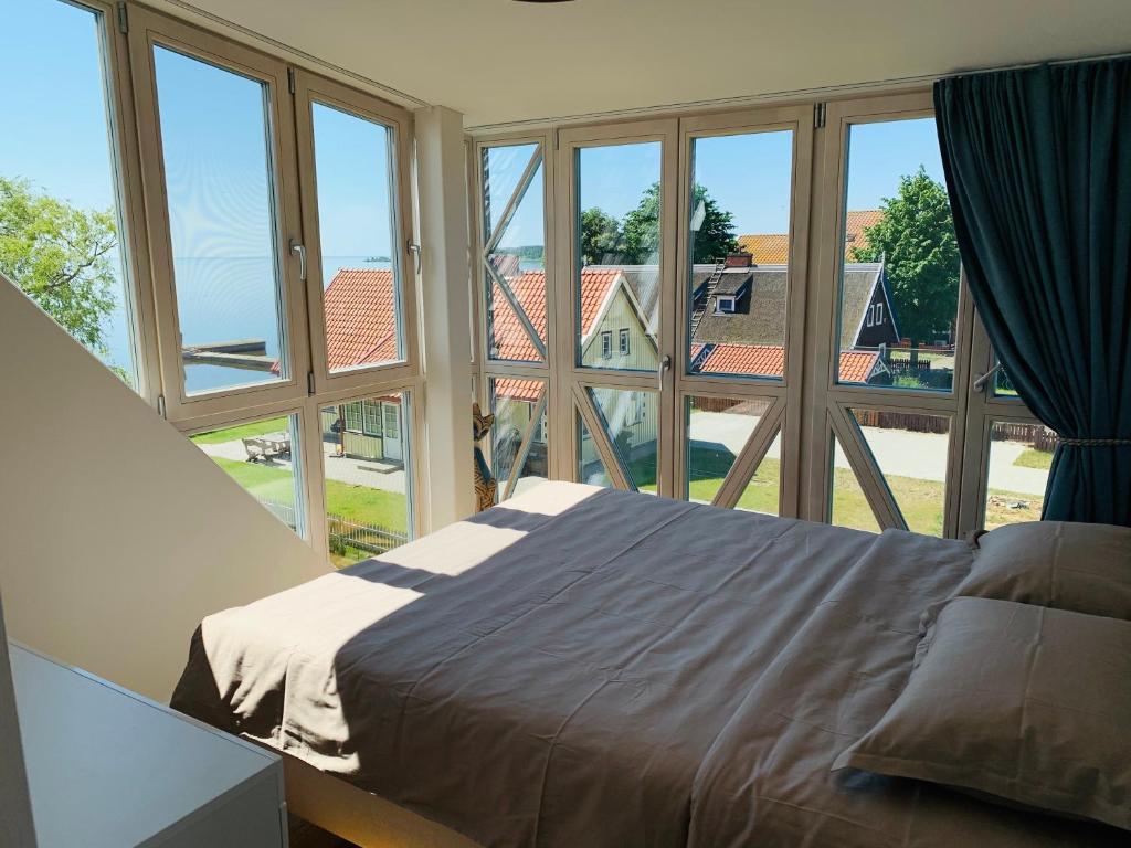 a bedroom with a bed and large windows at Lagoon Attic Apartment Pervalka in Pervalka
