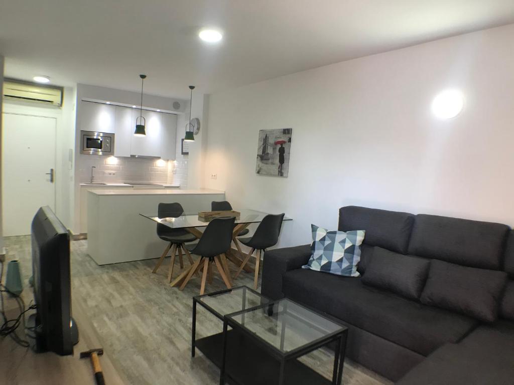 a living room with a couch and a table with chairs at Apartmento Apartaclub La Barrosa 223 in Chiclana de la Frontera
