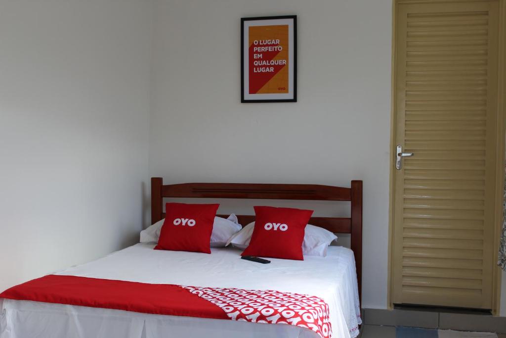a bedroom with a bed with two red pillows at OYO Pousada Paraná in Cuiabá