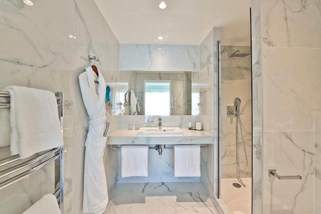 a white bathroom with a sink and a shower at Hôtel La Villa Port d'Antibes & Spa in Antibes