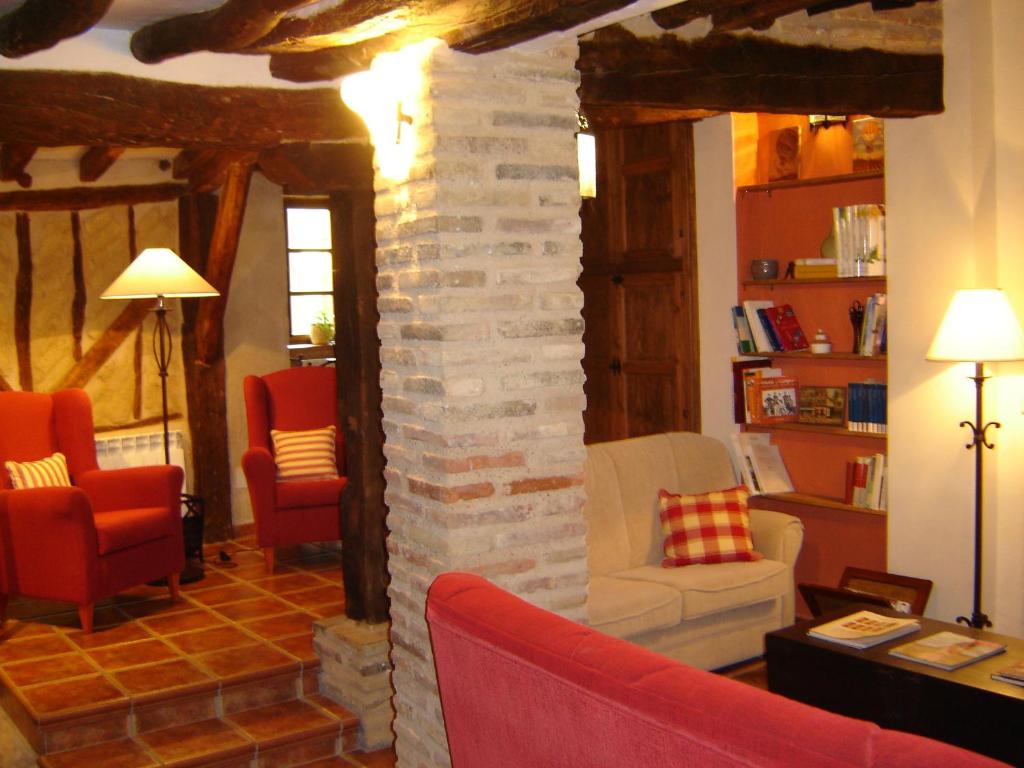 - un salon avec une cheminée en pierre et 2 chaises dans l'établissement Casa Rural El Encuentro, à Villalón de Campos
