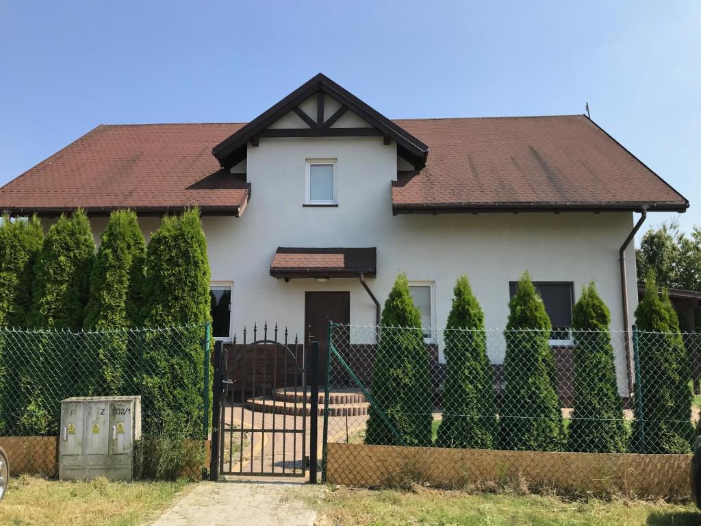 une maison blanche avec un portail et une clôture dans l'établissement Pokoje gościnne Anna, à Rewa