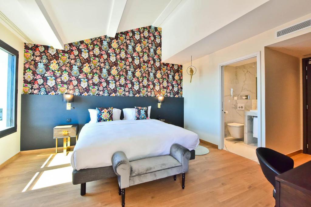 a bedroom with a large bed with a floral accent wall at Hôtel La Villa Port d'Antibes & Spa in Antibes