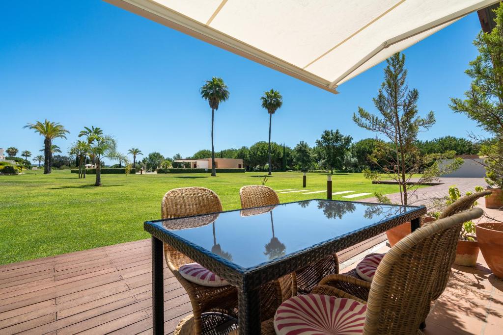 eine Terrasse mit einem Tisch und Stühlen sowie einem Grasfeld in der Unterkunft Monte Laguna duplex by Intiholidays in Vilamoura