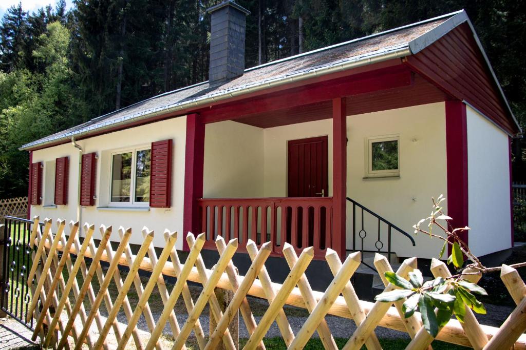 une petite maison avec une clôture devant elle dans l'établissement Erzgebirgsidyll Breitenbrunn - Waldhaus, à Neuer Anbau
