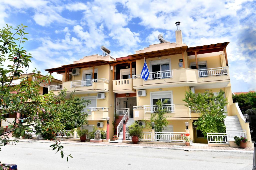 duży żółty budynek z niebieską flagą w obiekcie House Ilias w mieście Sarti