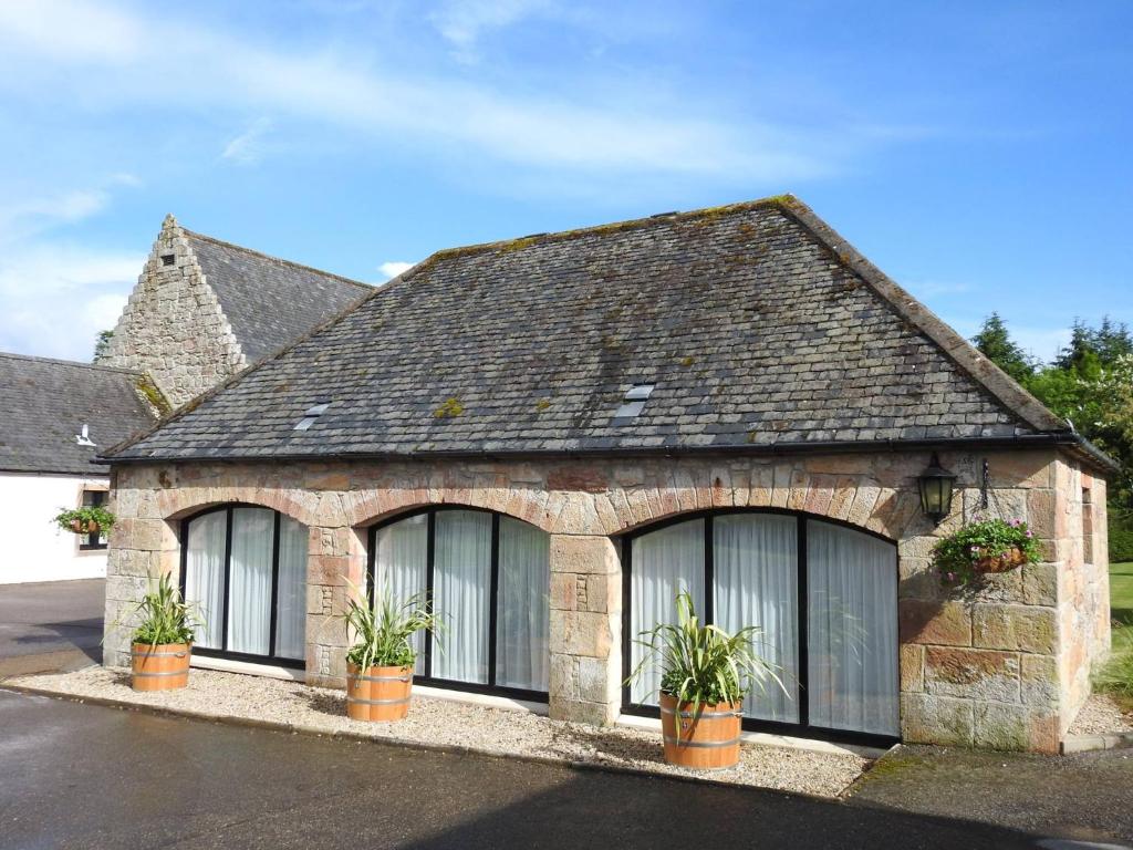 een huis met ramen en planten ervoor bij Balnagown Estates Peat Cottage in Kildary