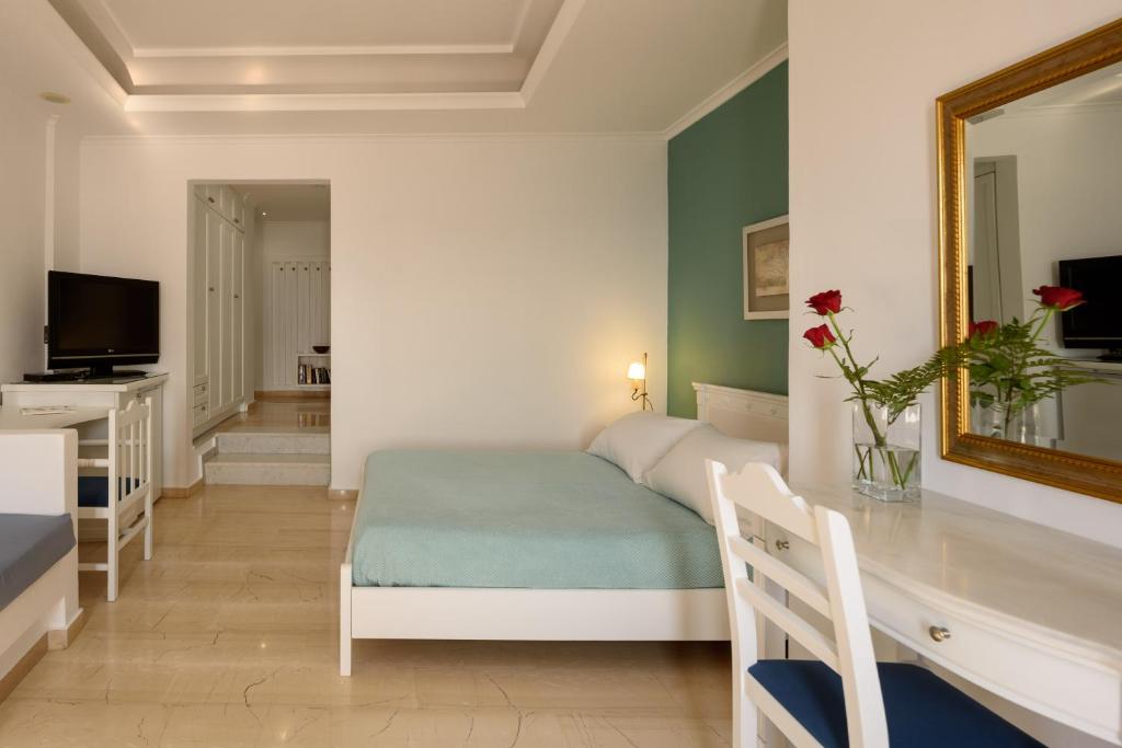 a bedroom with a bed and a desk and a mirror at Villa Renos Hotel in Fira