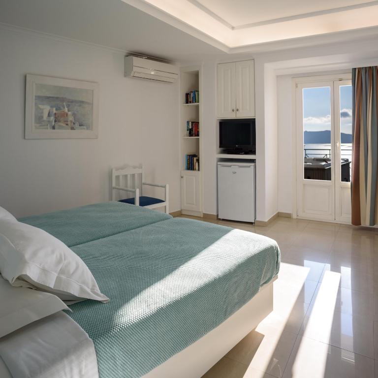a bedroom with a bed with a view of the ocean at Villa Renos Hotel in Fira