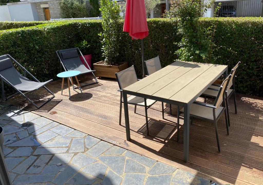una mesa de madera con sillas y una sombrilla en el patio en Appartement terrasse privée grande plage à 100 m - Parking gratuit, en Saint-Cast-le-Guildo