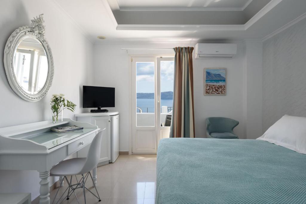 a bedroom with a bed and a desk and a computer at Villa Renos Hotel in Fira
