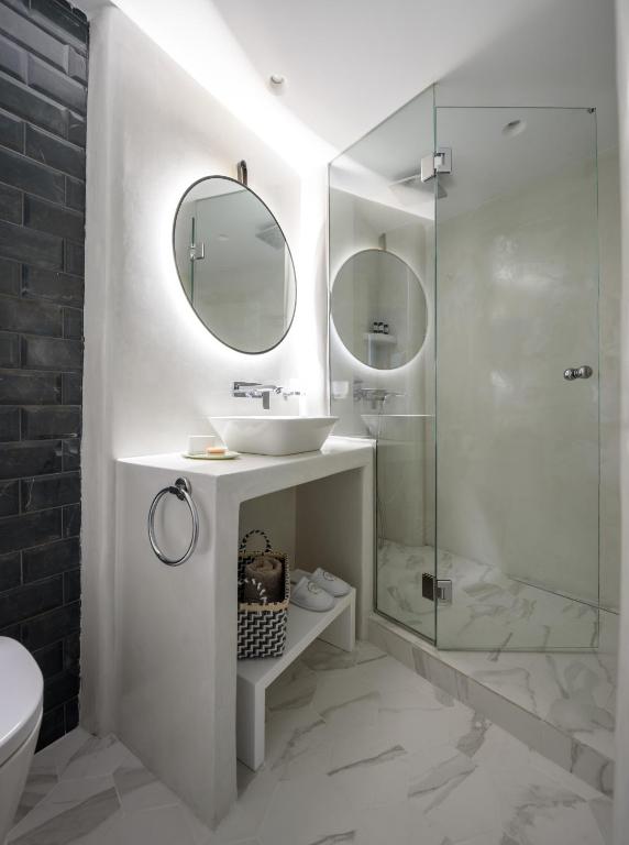 a white bathroom with a sink and a shower at Villa Renos Hotel in Fira
