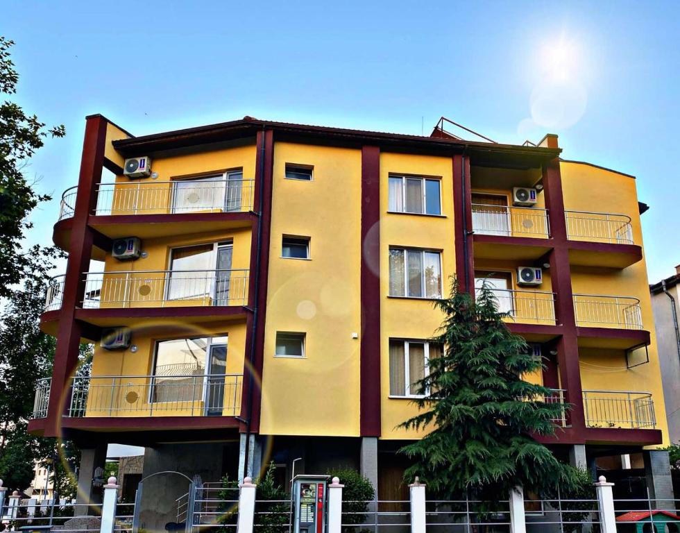 a yellow building with a tree in front of it at Guest House Kostovi in Kiten