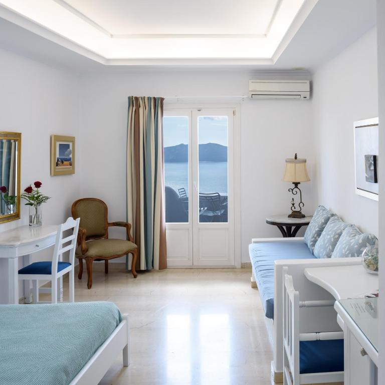 a white living room with a couch and a window at Villa Renos Hotel in Fira