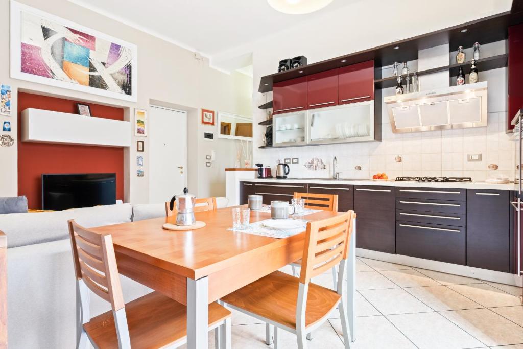 uma cozinha e sala de jantar com uma mesa de madeira e cadeiras em Giardino Vignoli Functional Apartment em Bolonha