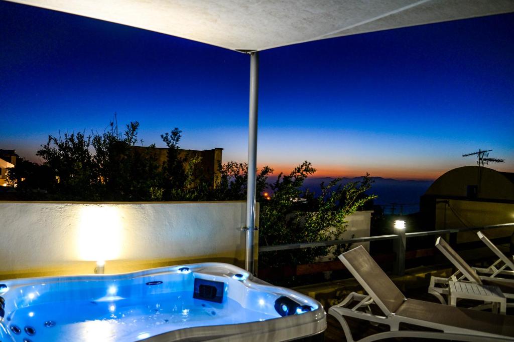a jacuzzi tub sitting on a patio with chairs at Sunrise onLava in Oia