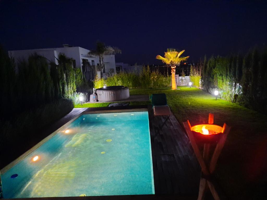 ein Schwimmbad in einem Garten in der Nacht in der Unterkunft SUPERBE VILLA AVEC PISCINE PLAGES DES NATIONS in Rabat