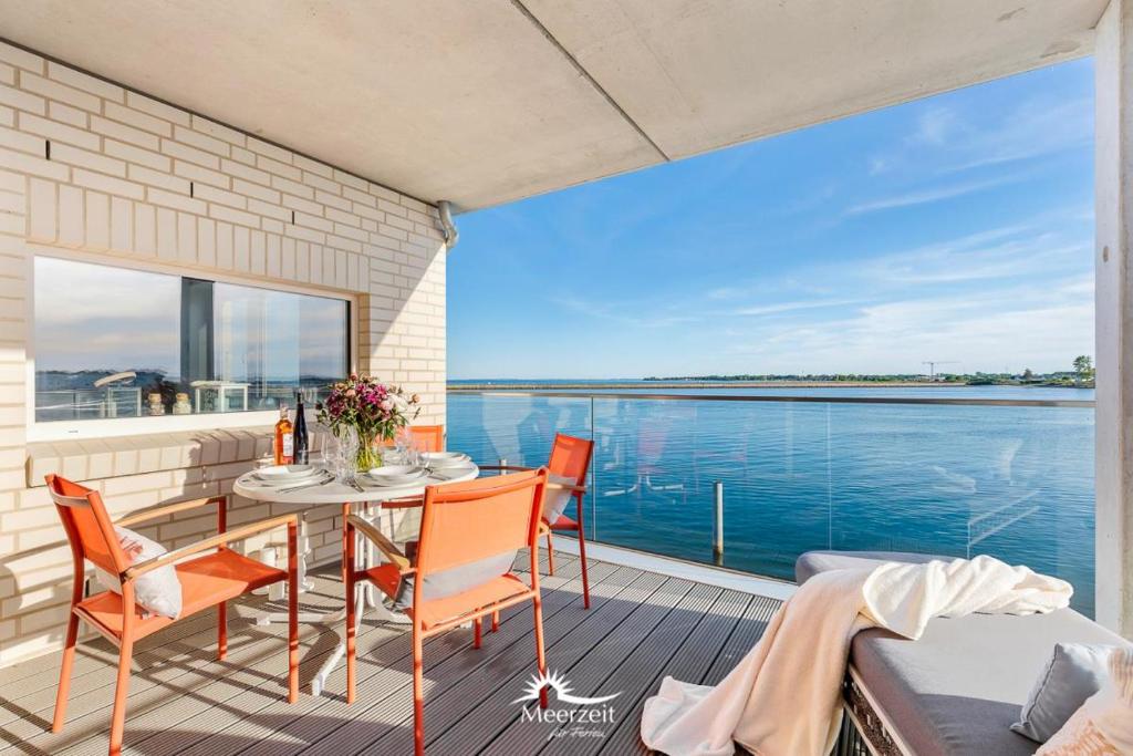 a balcony with a table and chairs and a view of the water at Horizont- direkt am Wasser, Hafenblick, Fahrstuhl, Sauna, ueberdachter Balkon in Olpenitz