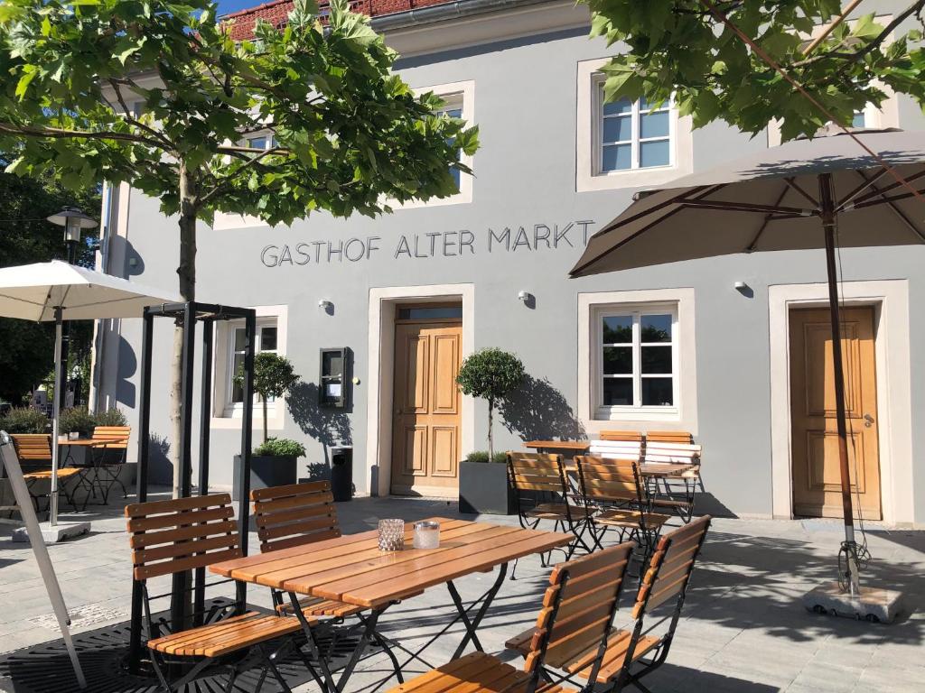 Gasthof Alter Markt في لوسهايم: مجموعة طاولات وكراسي أمام المبنى