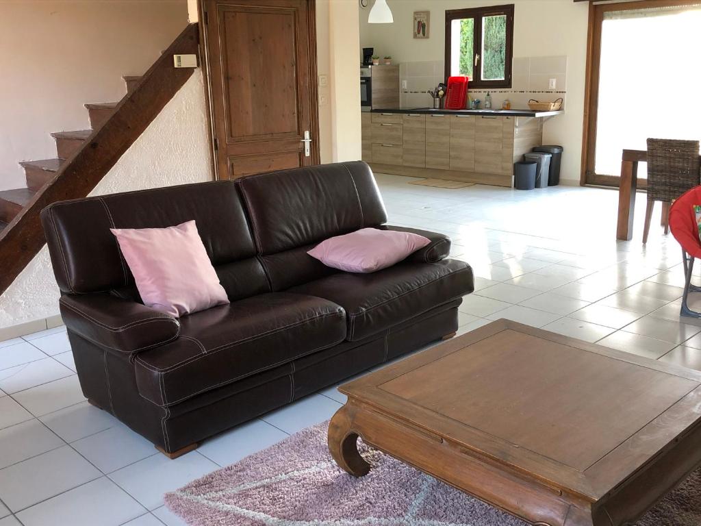 a living room with a leather couch and a coffee table at Fermette 3ch - 6p au pays du coquelicot by La Source d'OrFée in Courcelette