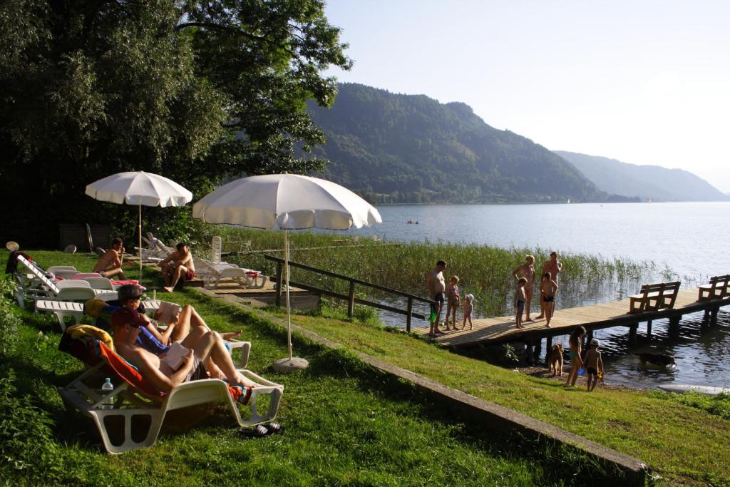 un gruppo di persone seduti su sedie a sdraio vicino a un lago di Seehaus Karantanien am Ossiacher See a Ossiach