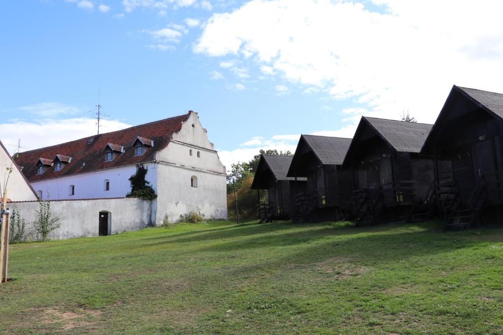 a large white and black building on a grass field at tvrz Holešice Orlická přehrada - Chaty in Kamenice