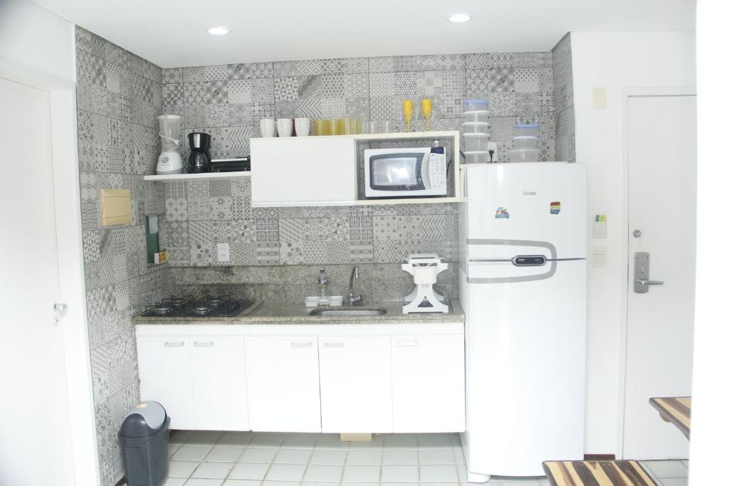 a kitchen with white cabinets and a white refrigerator at Ancorar Flat Resort 5202 in Ipojuca