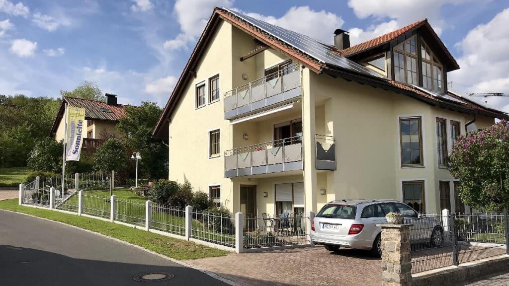 ein weißes Haus mit einem davor geparkt in der Unterkunft Ferienwohnungen Sonnleite in Friedenfels