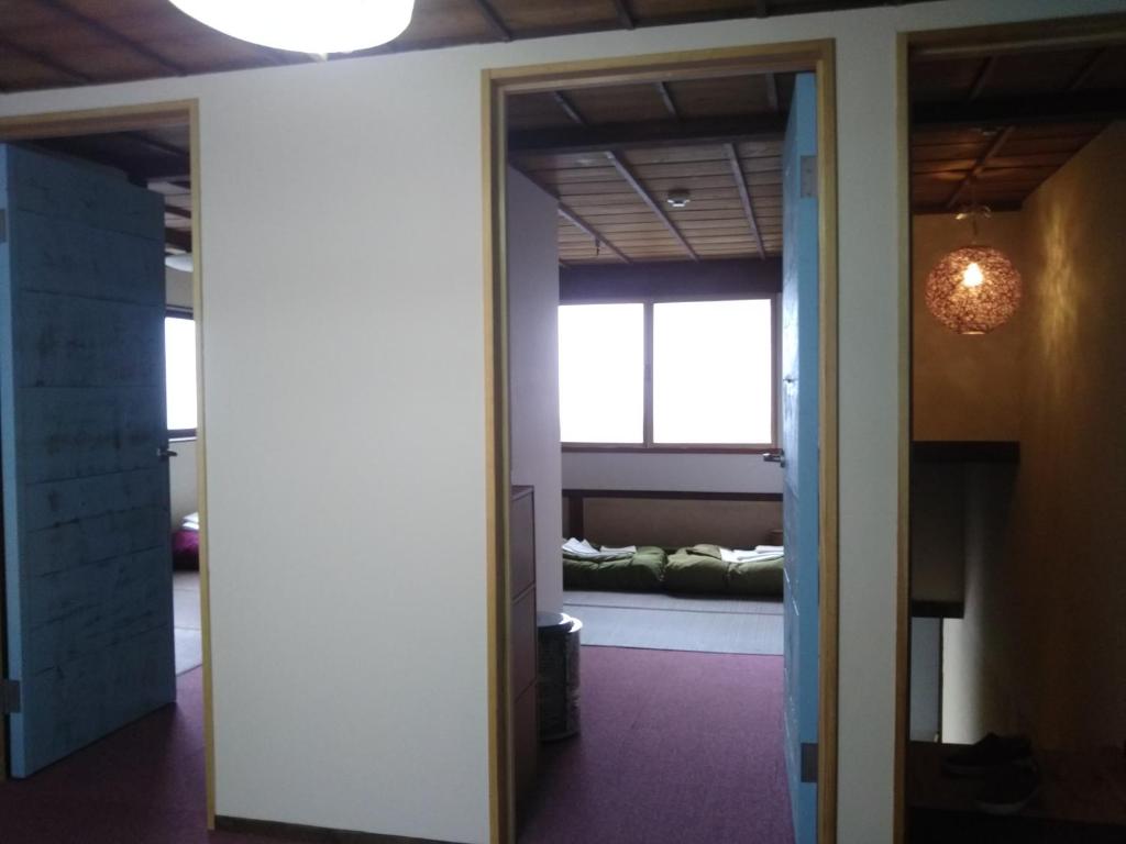 um corredor com um quarto com uma cama numa janela em はんこＩＮＮ お城のアパート Hanko INN Private aparments nearby castle em Matsumoto